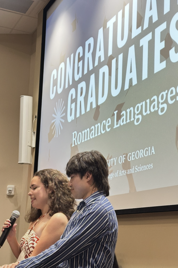 Two graduates hold mic and smile at ceremony