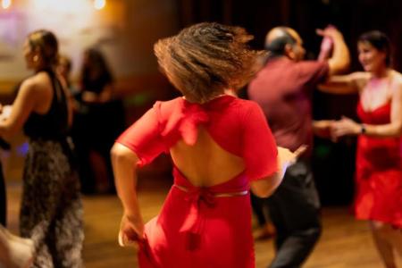 Dancing woman wearing a red dress with other dancers in the background